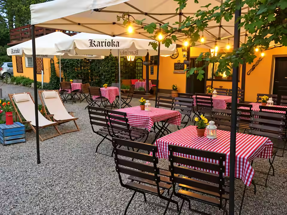 Wieczorem w ogrodzie Karioki: stoliki w czerwoną kratę, lampiony i światełka pod parasolami