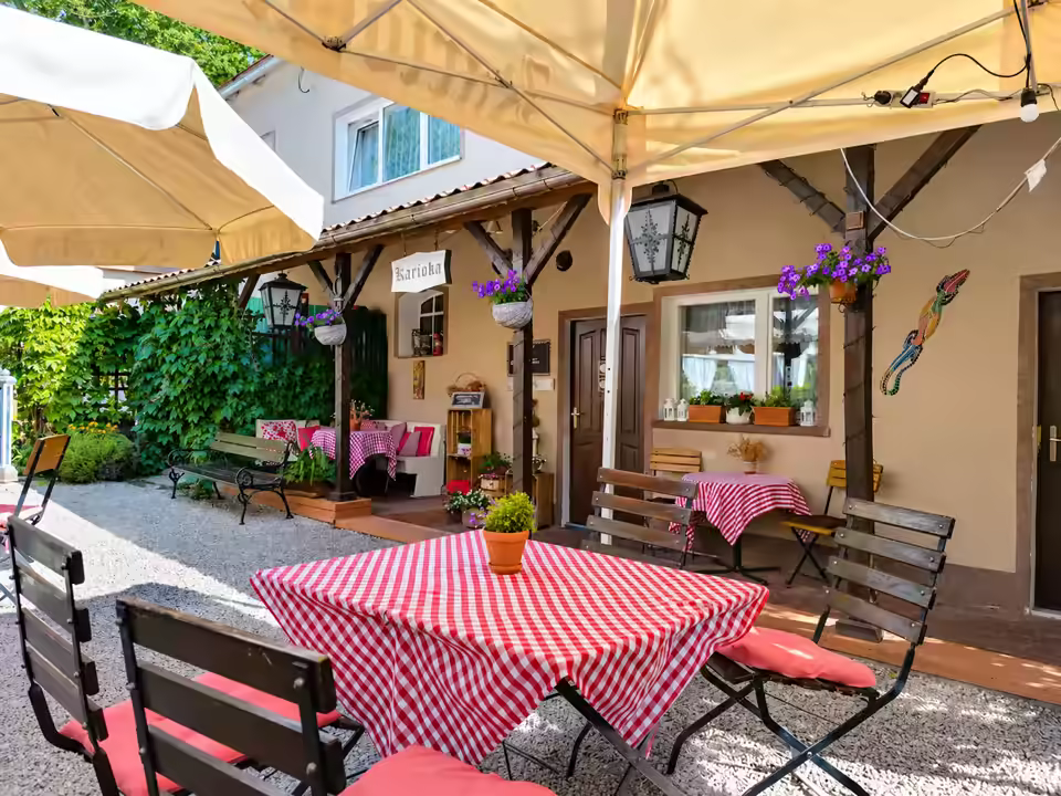 Stolik w czerwoną kratę pod parasolem na patio przy wejściu do baru
